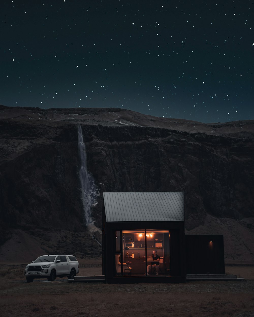 a car parked in front of a house with a waterfall in the background