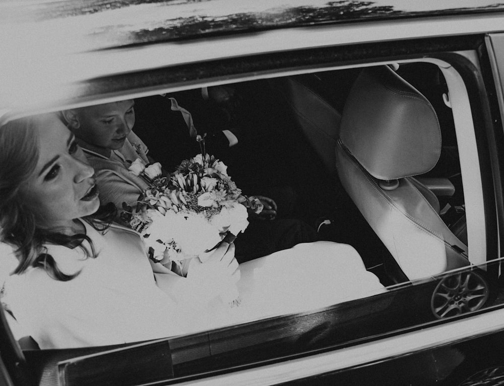 a woman sitting in a car with a bouquet of flowers