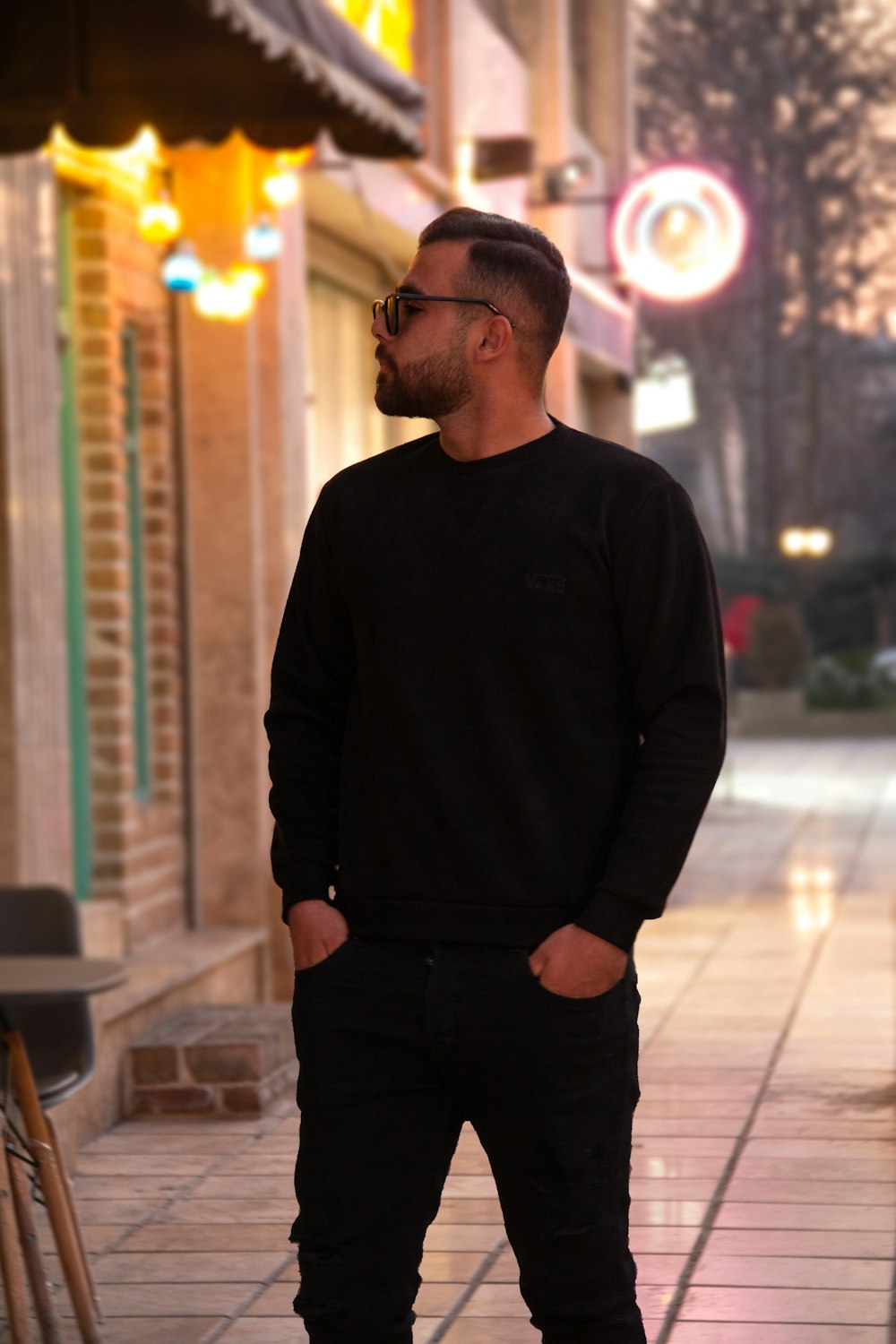 a man standing on a sidewalk with his hands in his pockets