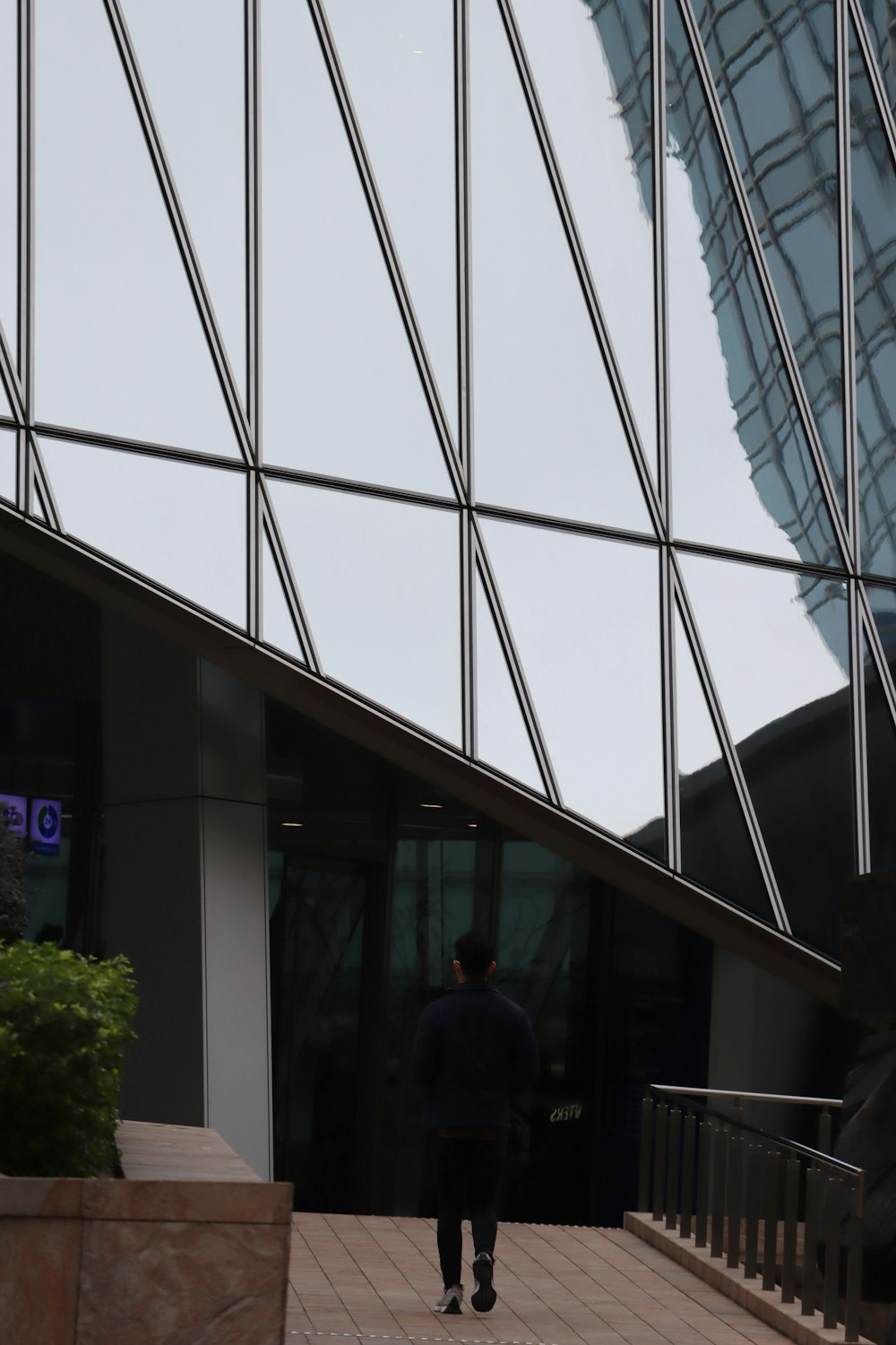 a man walking down a sidewalk next to a tall building