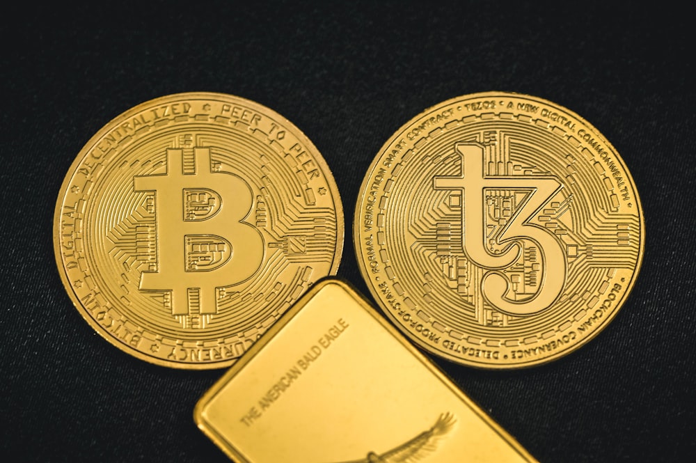 two gold bitcoins sitting next to each other
