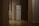 A dimly lit hallway with wooden floors features a white refrigerator situated against a wall. There is a radiator next to a window on the left side, and the space has a minimalistic appearance with neutral-colored walls.