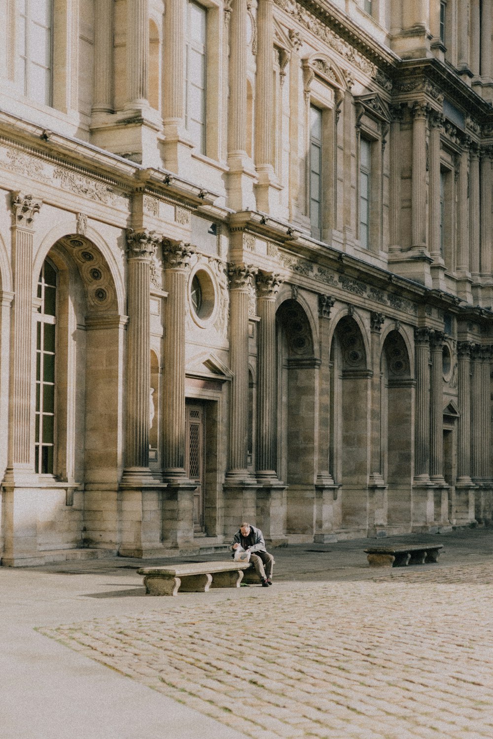 a person sitting on a bench in front of a building