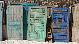 A row of restored vintage doors leaning against a rustic brick wall, each telling its own story.