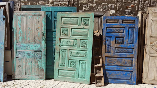 A row of restored vintage doors leaning against a rustic brick wall, each telling its own story.