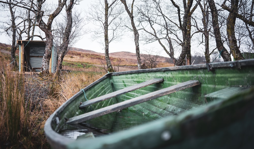 a green boat sitting on top of a grass covered field