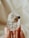 A hand is holding a clear crystal with dark inclusions inside. The background is out of focus, featuring soft, neutral colors that enhance the transparency and texture of the crystal.