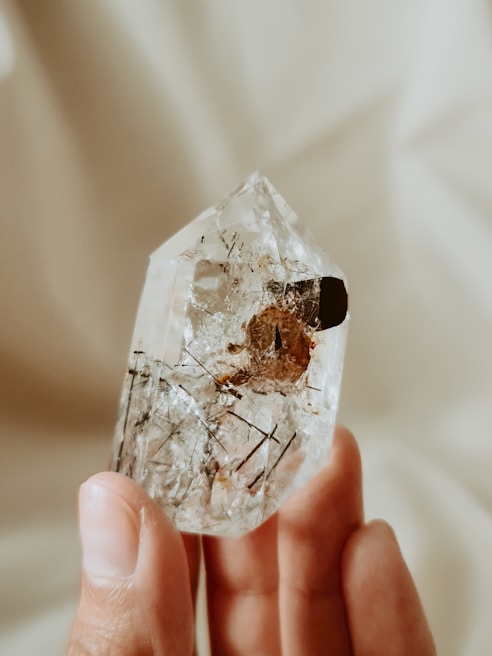 Close-up of a hand holding a smooth crystal under natural daylight