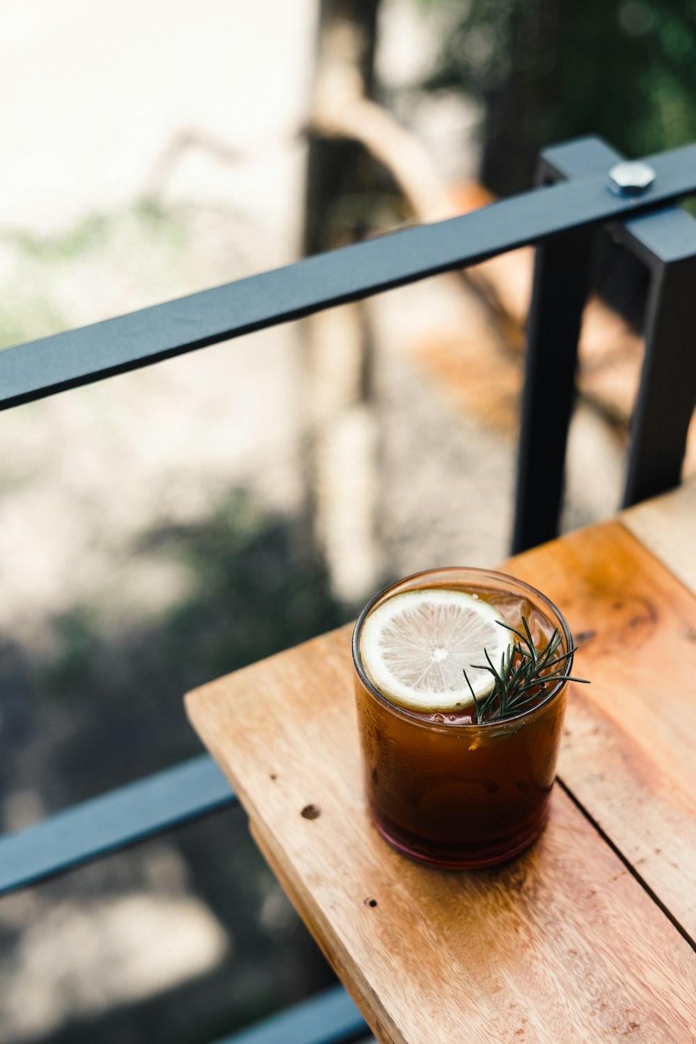 a drink on a wooden table with a fence in the background