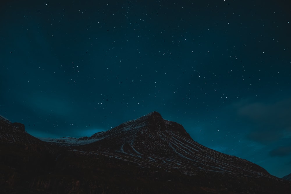 a night sky with stars above a mountain