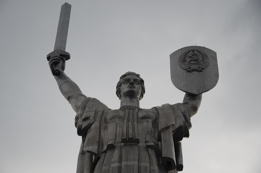 uma estátua de um homem segurando uma espada e escudo