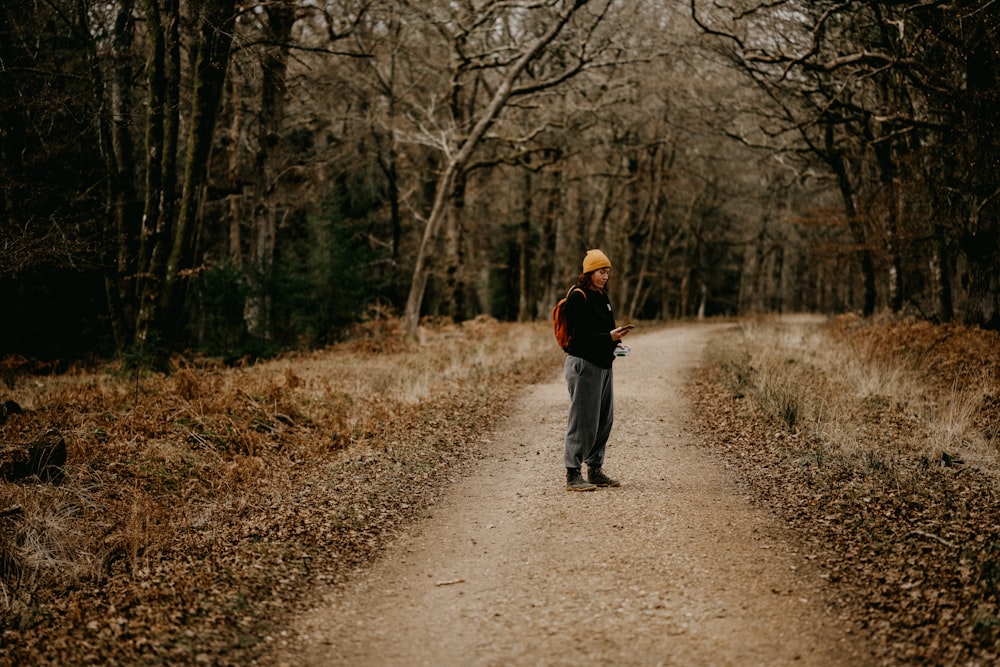 a person standing on a dirt road in the woods