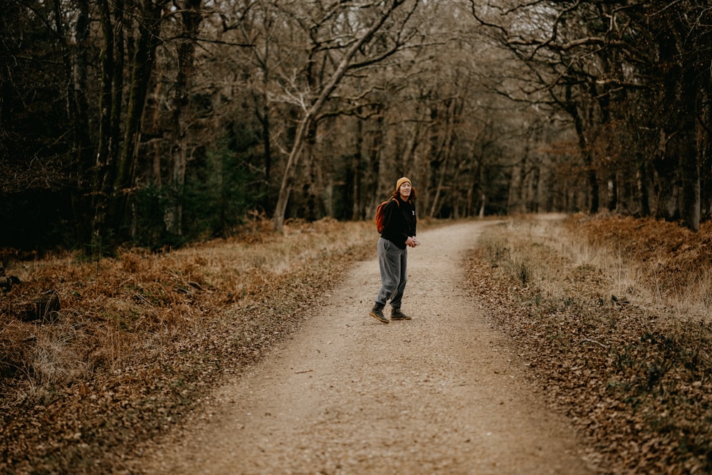 a man walking down a dirt road in the woods