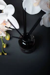 a black vase filled with white flowers on top of a table