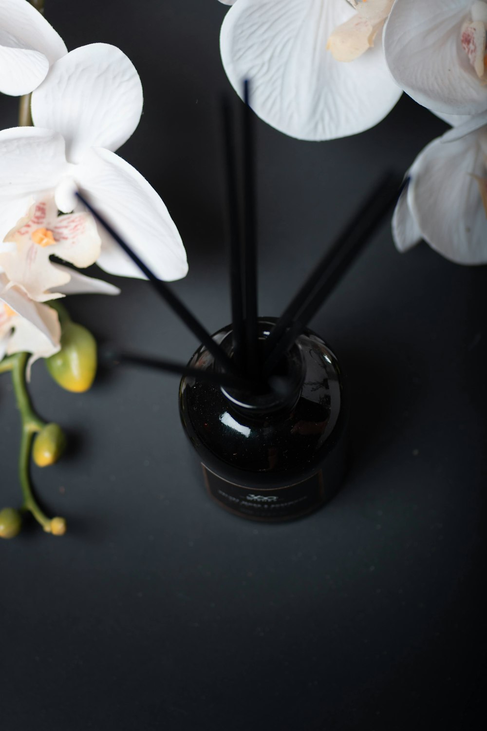 a black vase filled with white flowers on top of a table