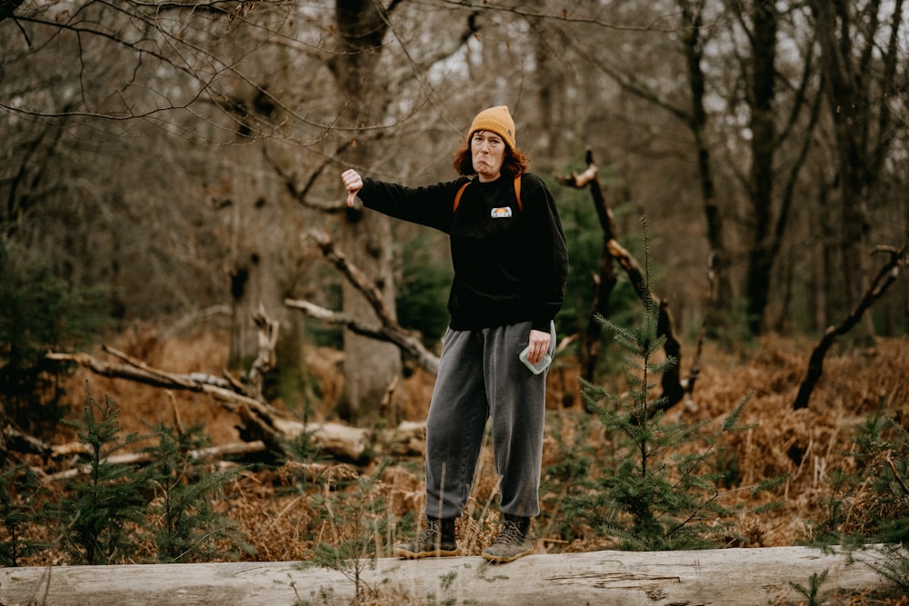 a man standing on a log in the woods