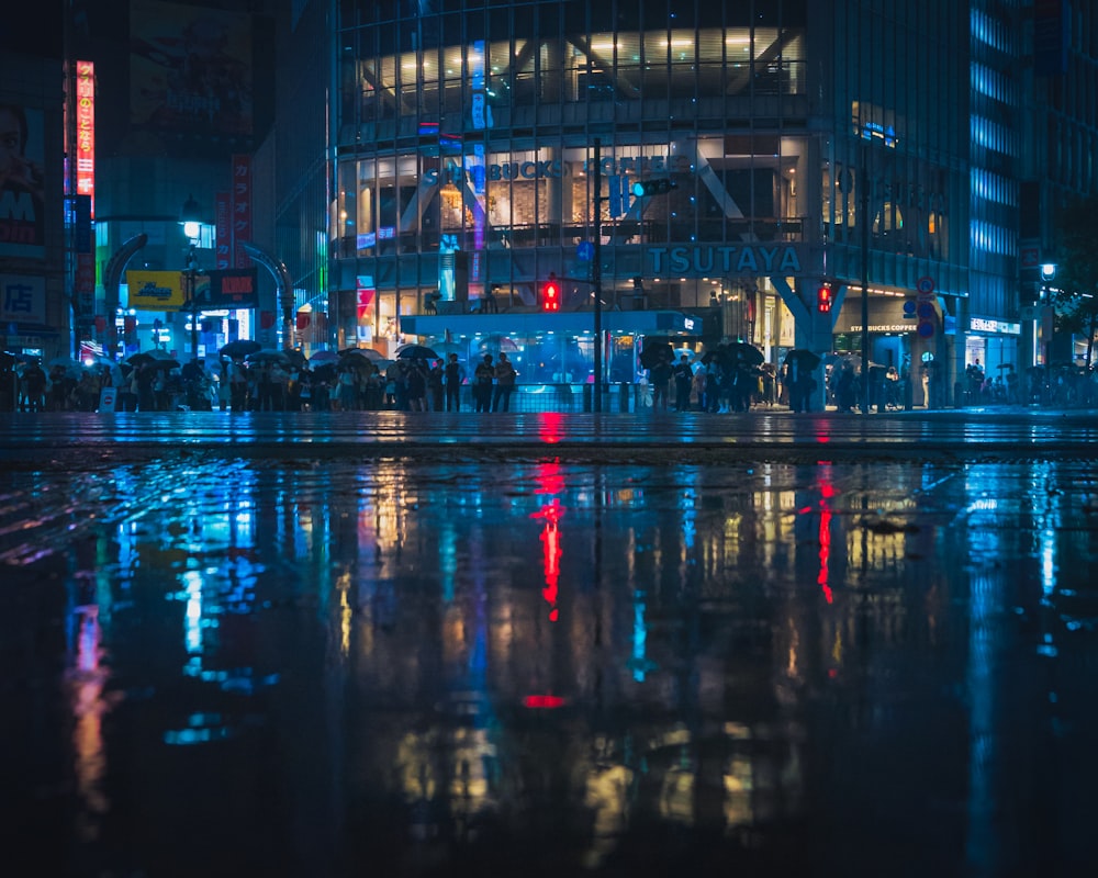 a group of people standing on a wet street at night