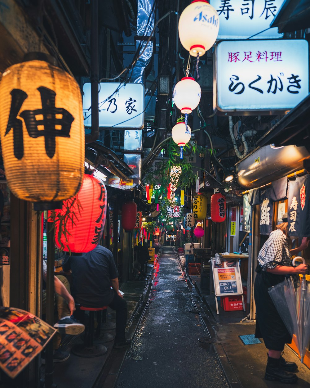 a narrow alley with asian signs hanging from the ceiling