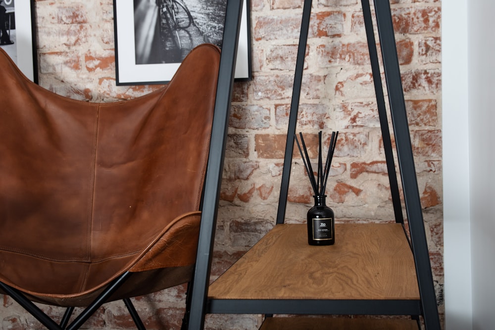 a brown leather chair next to a brick wall