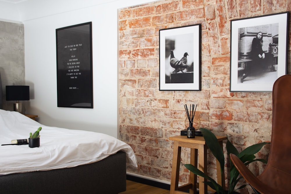a bedroom with a brick wall and pictures on the wall