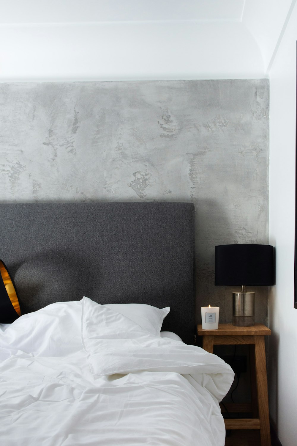 a bed with white sheets and a gray headboard