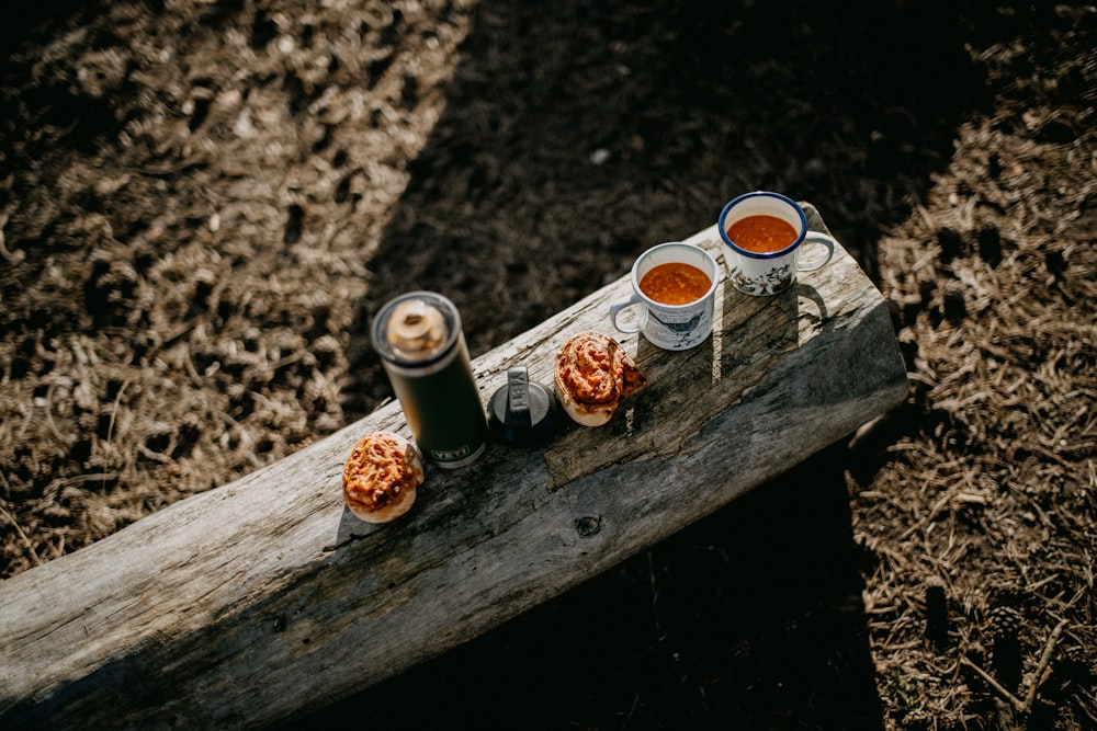 three cups of tea sit on a piece of wood