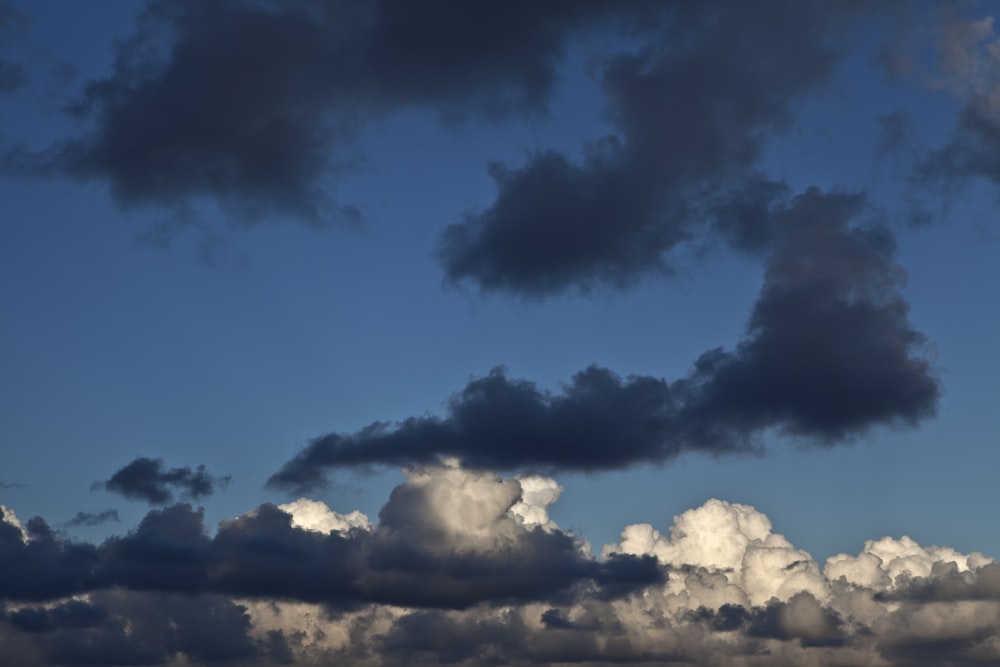 a plane flying through a cloudy blue sky