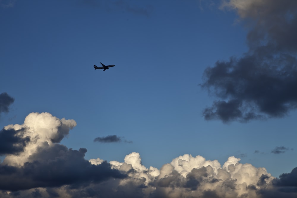 a plane flying through a cloudy blue sky