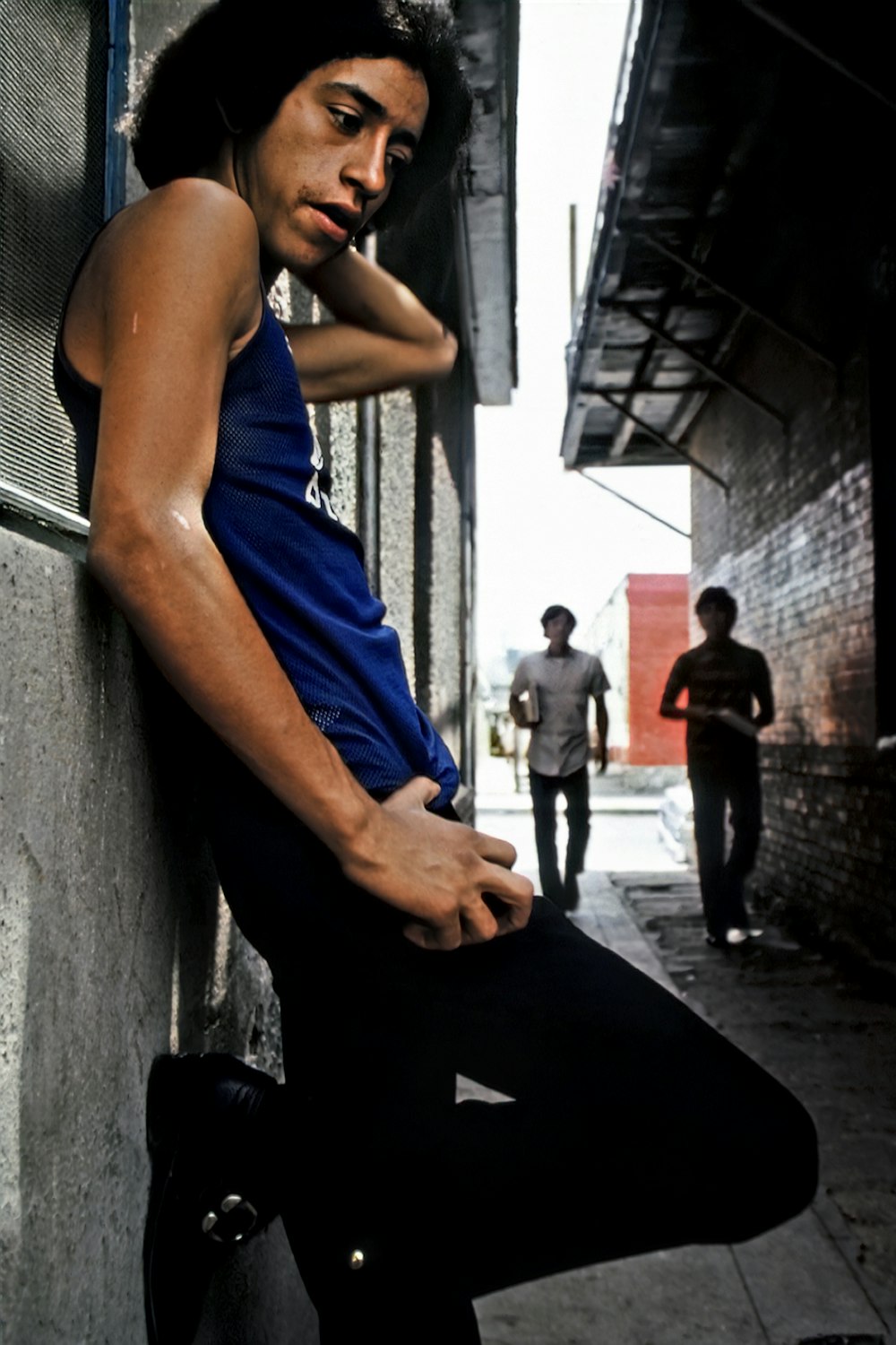 a man leaning against a wall with his hand on his hip