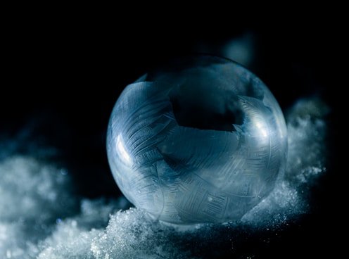 a glass ball sitting on top of a pile of snow