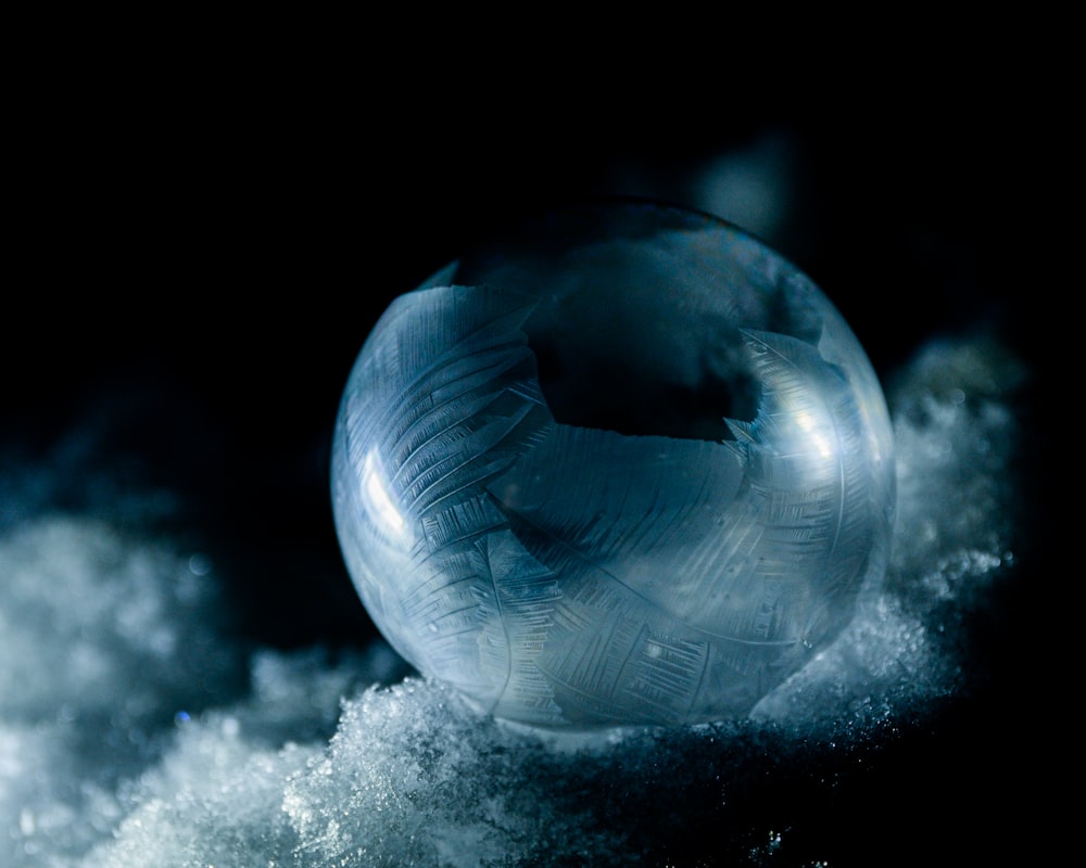 a glass ball sitting on top of a pile of snow