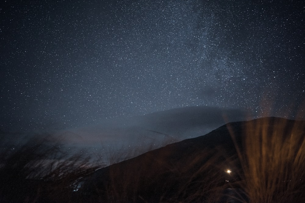 the night sky with stars above a mountain