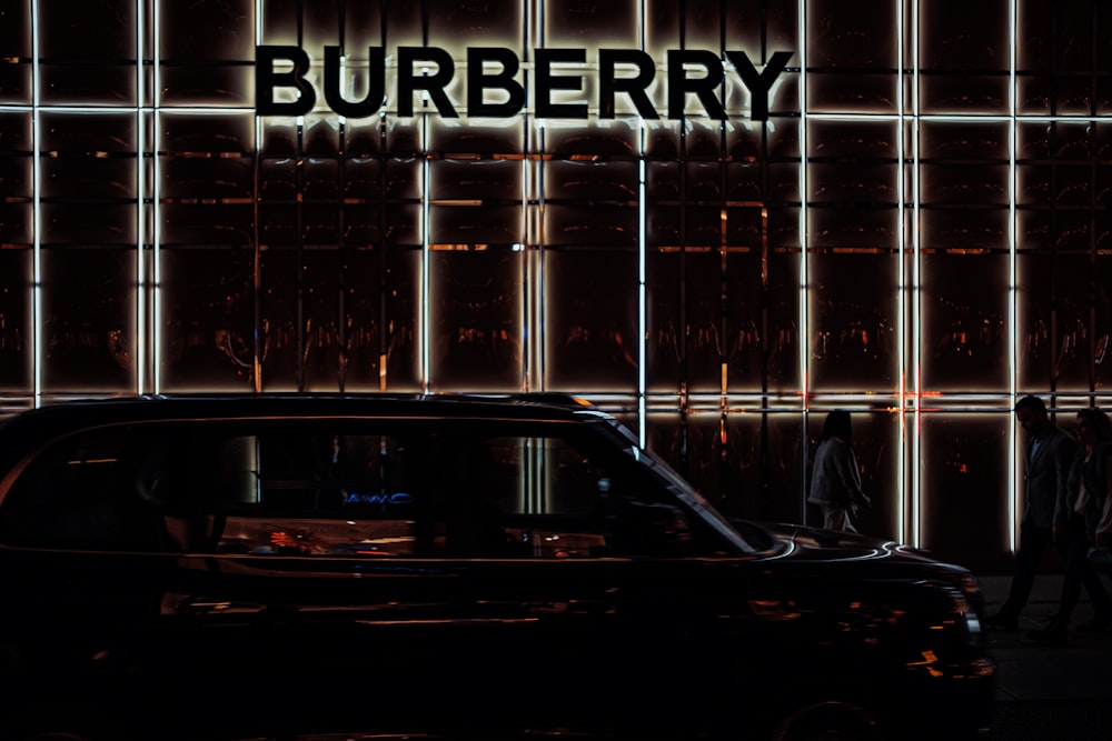 Une voiture noire garée devant un immeuble Burberry