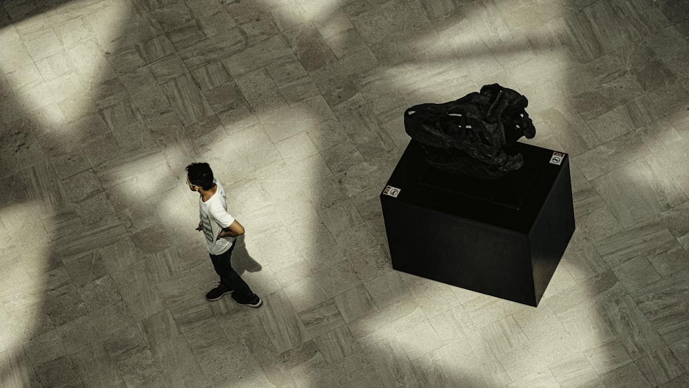 a person walking past a sculpture on a tiled floor