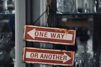 two red and white signs hanging from a metal pole