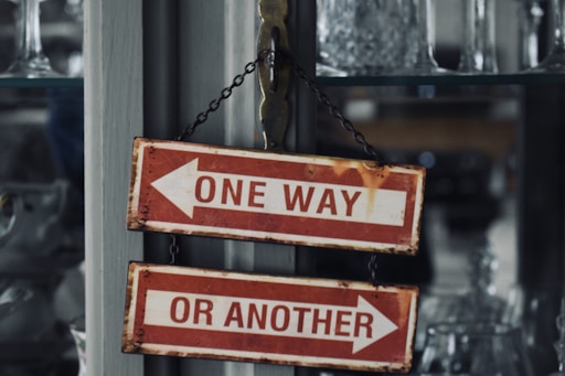 two red and white signs hanging from a metal pole