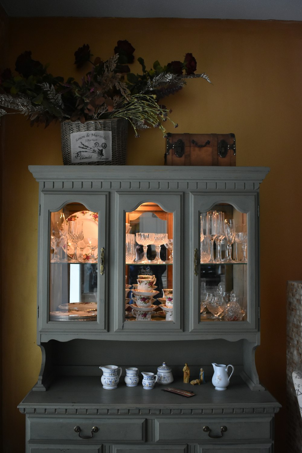 a china cabinet with glass doors and a vase on top of it