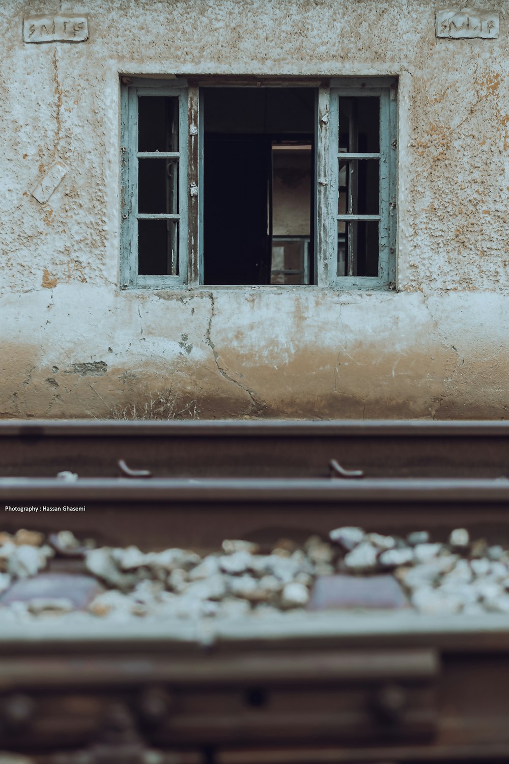 an old building with a broken window and a train track