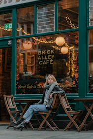 a woman sitting on a bench in front of a cafe