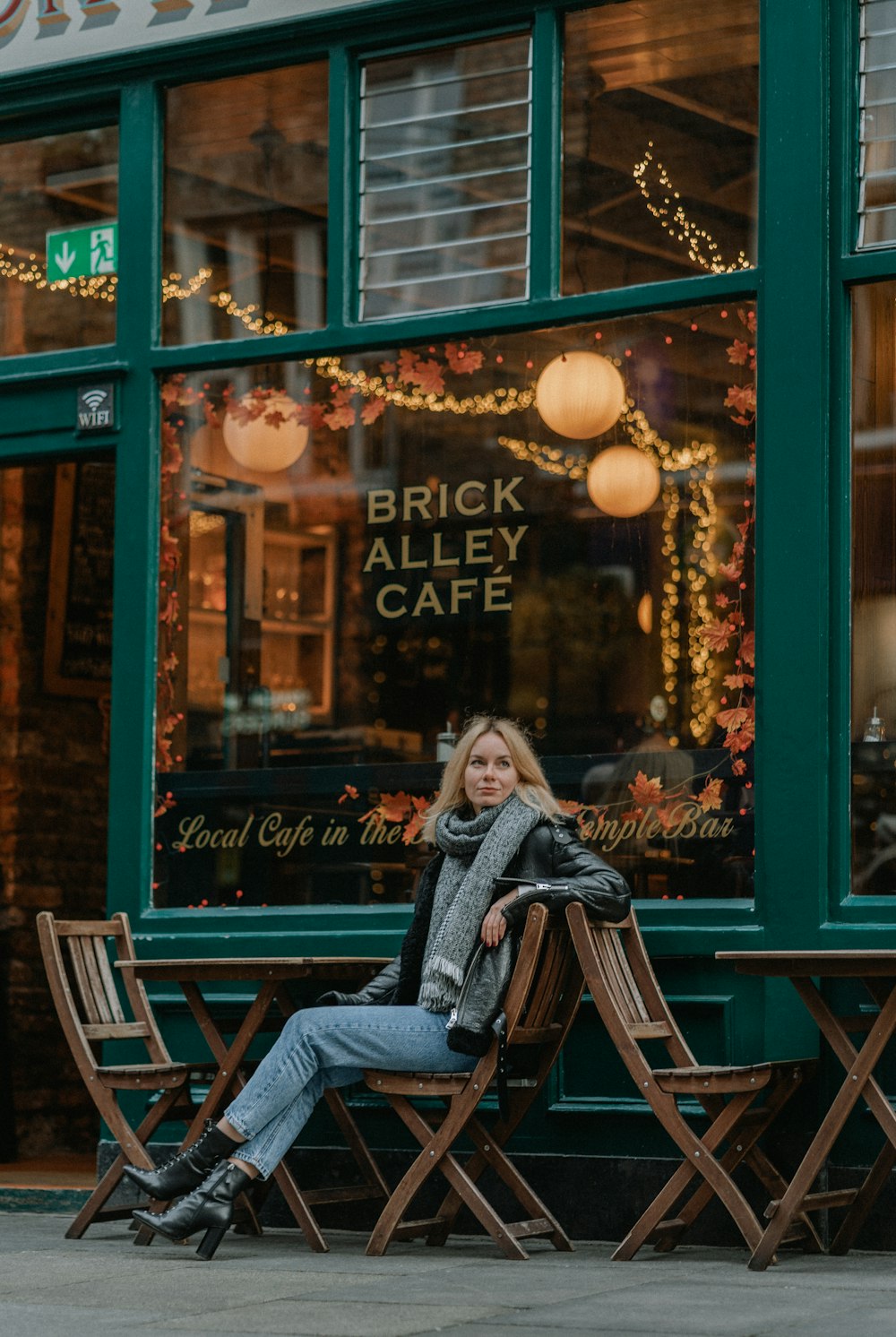a woman sitting on a bench in front of a cafe