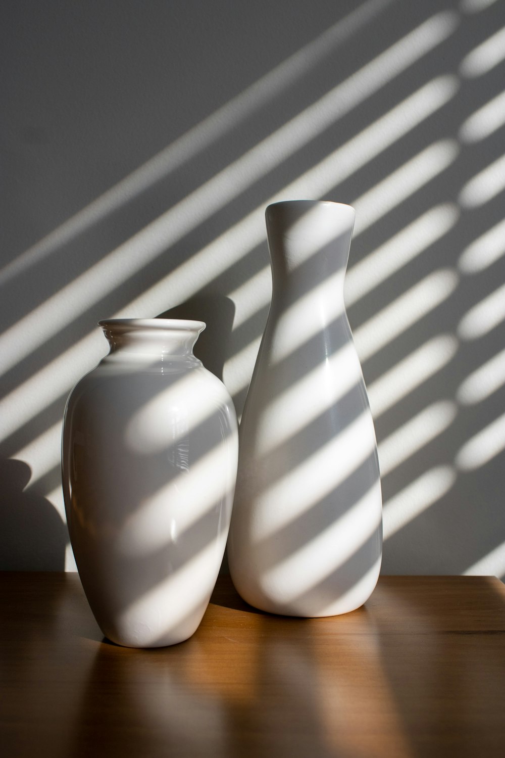 a couple of white vases sitting on top of a wooden table