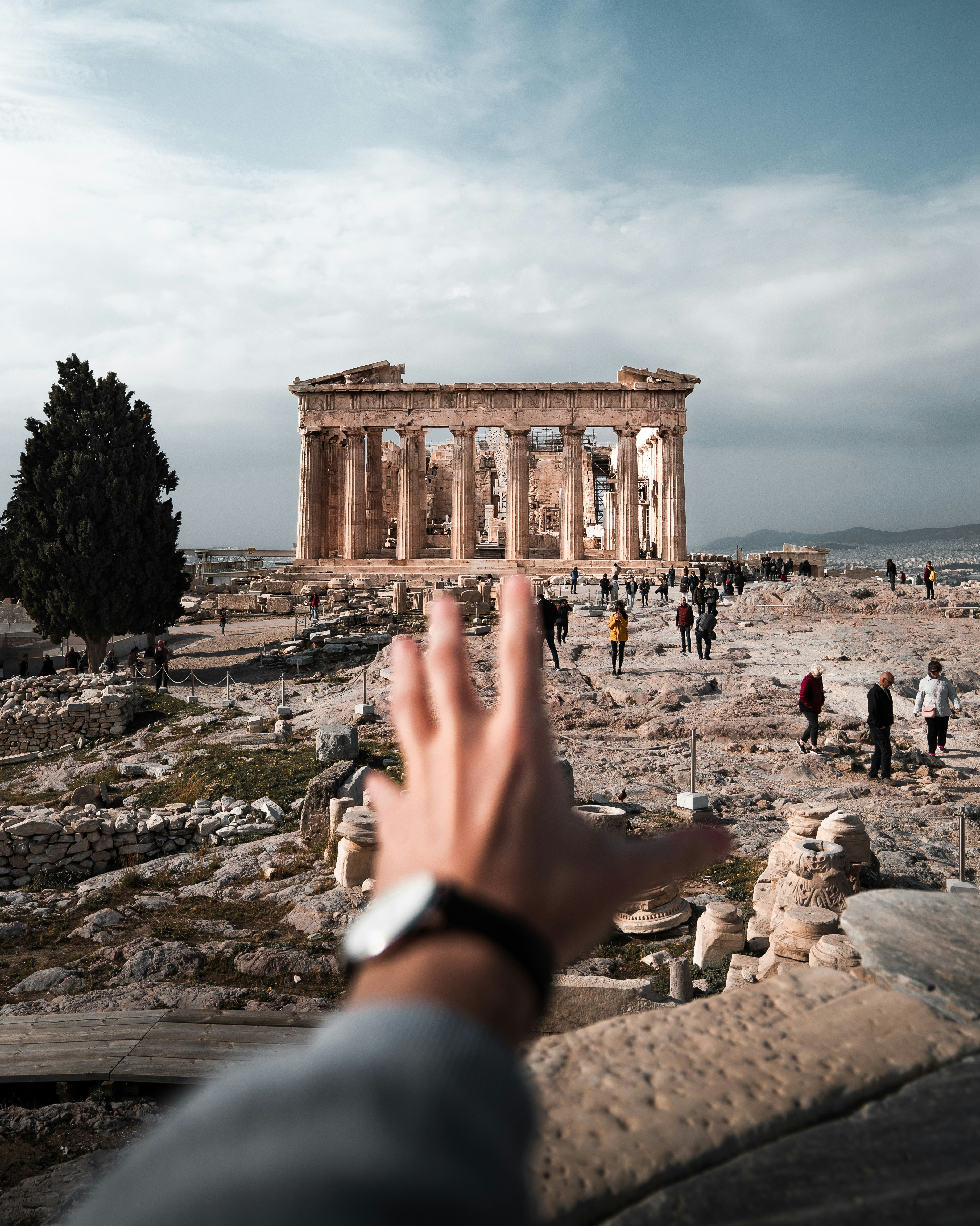 a hand reaching up towards the ruins of a building