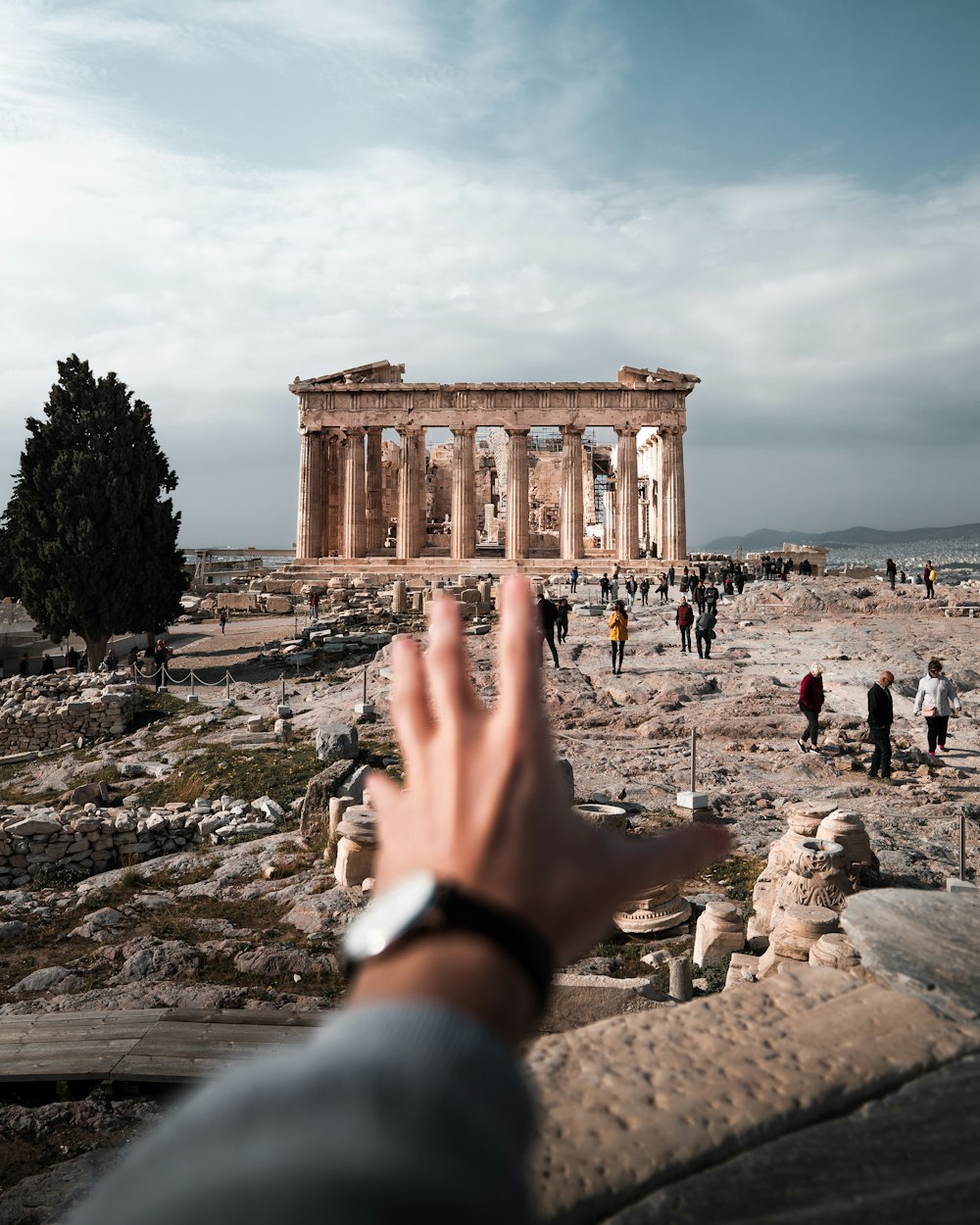 a hand reaching up towards the ruins of a building