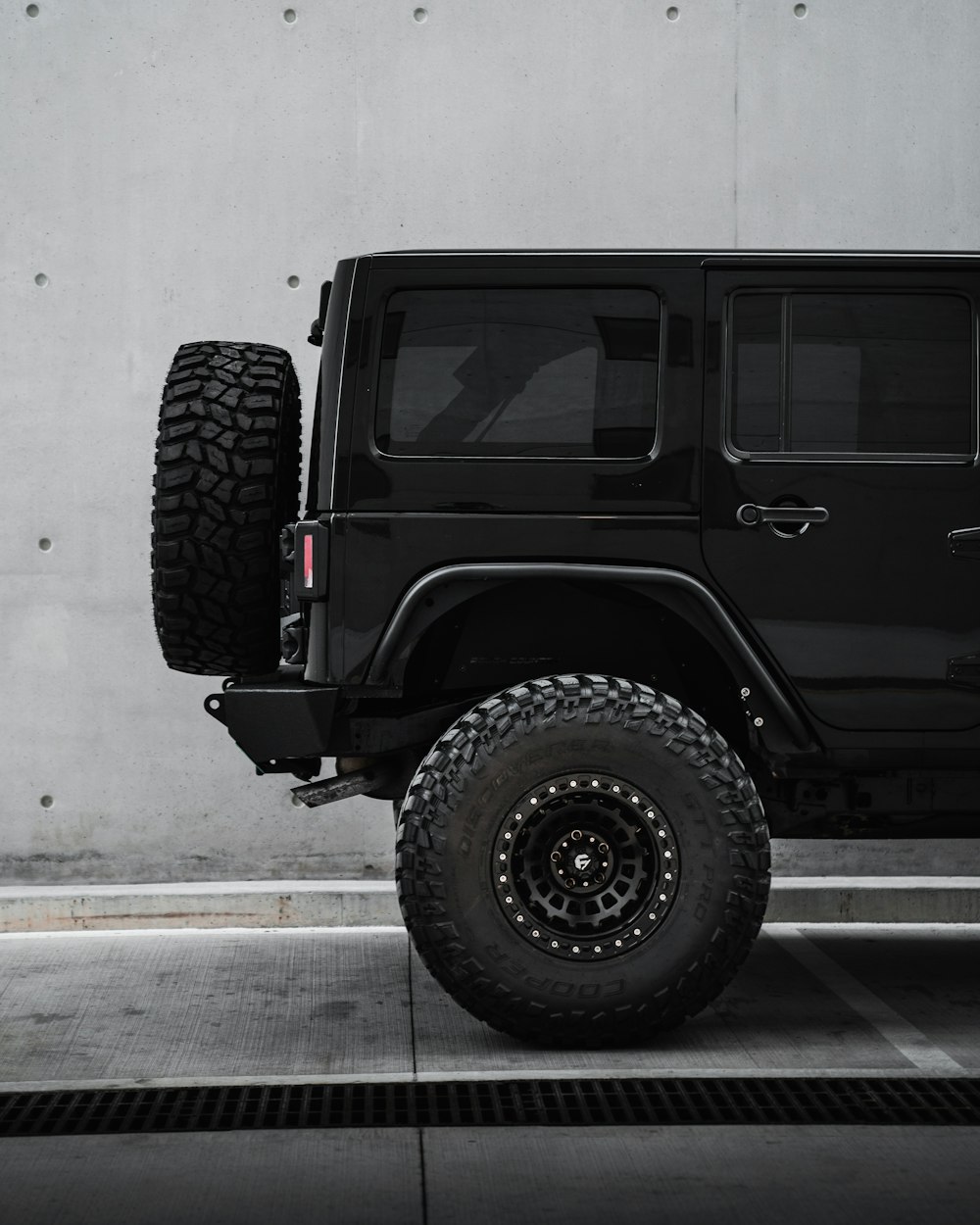 a black jeep is parked in a parking lot