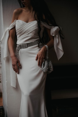 a woman in a white dress holding a purse