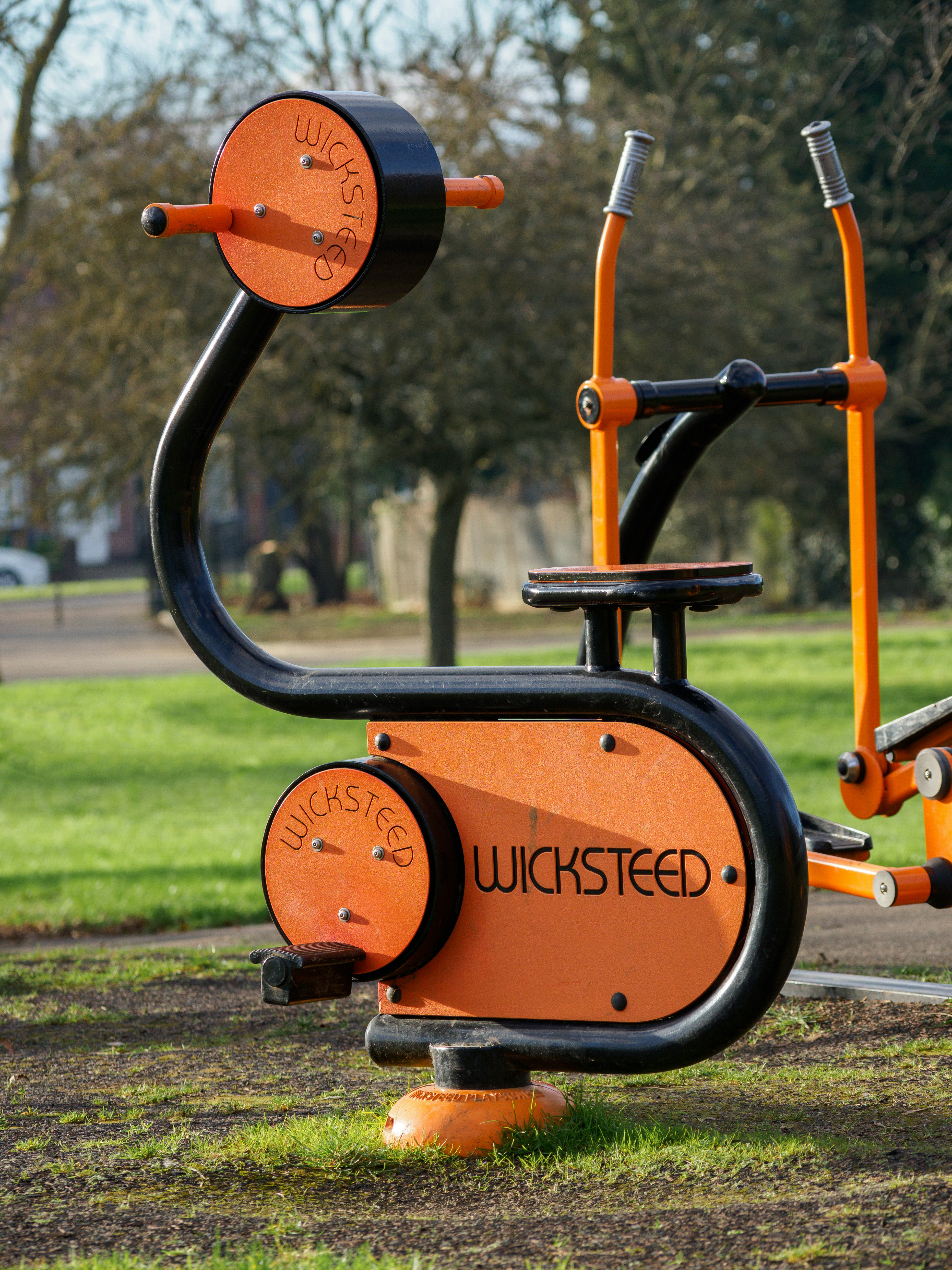 an orange and black exercise machine in a park