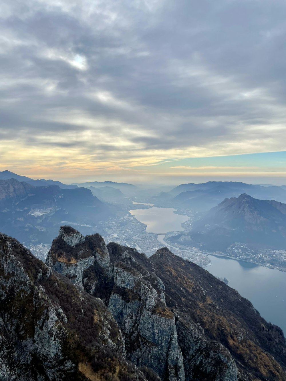 a man sitting on top of a mountain next to a lake