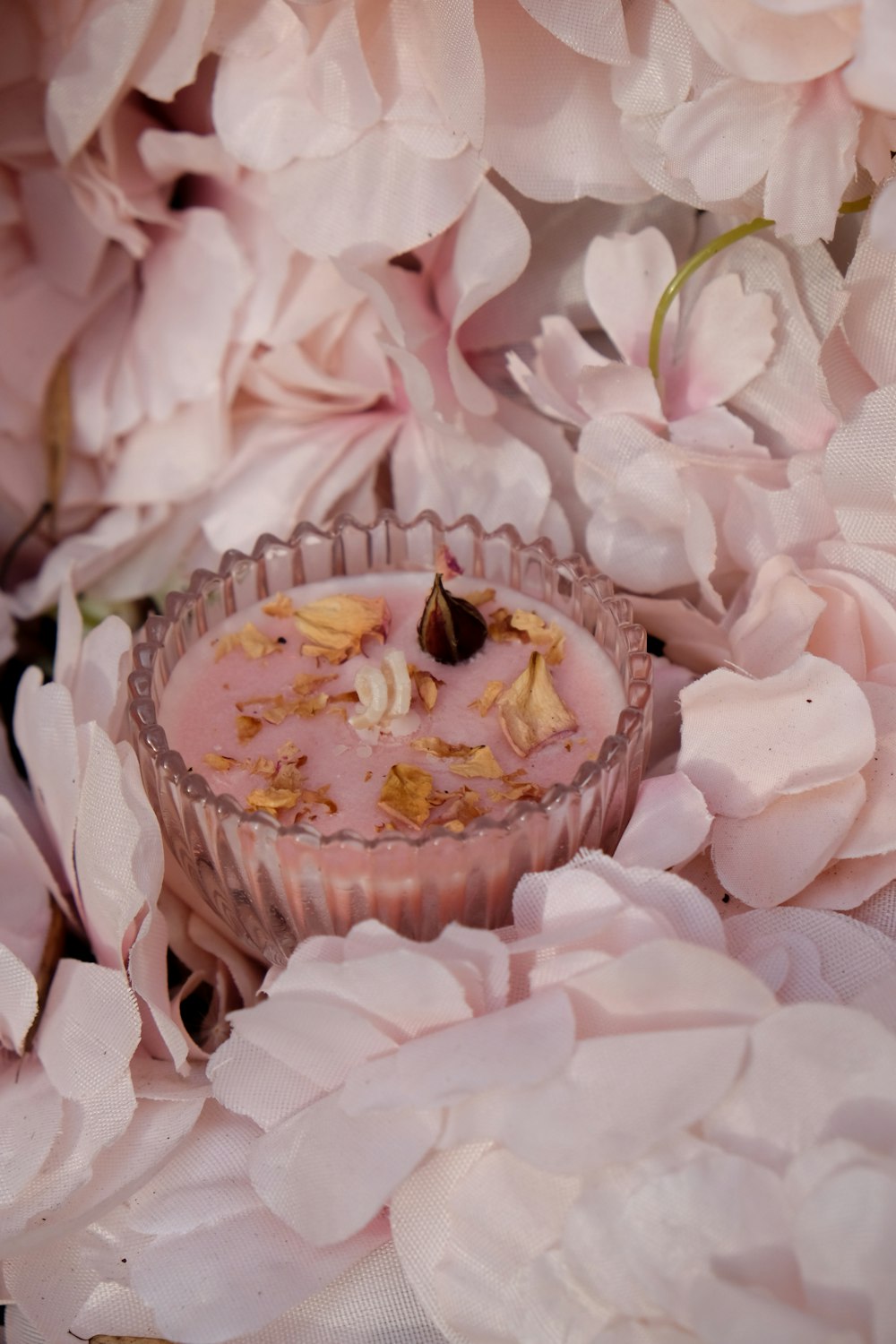 a cupcake sitting on top of a table surrounded by pink flowers