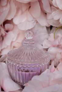 Elegant moisturizer jar with a warm rose lid, surrounded by fresh rose petals.