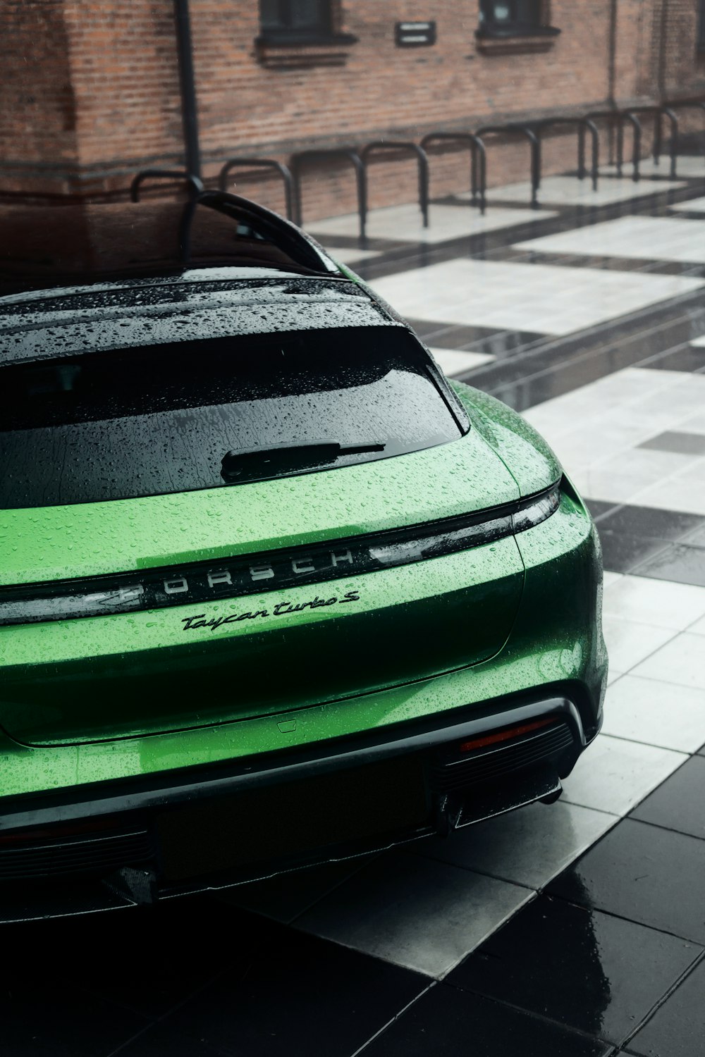 a green sports car parked in front of a brick building